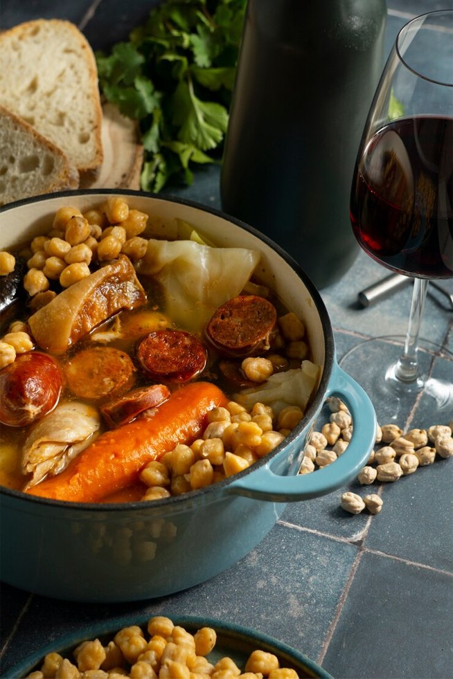 Olla de cocido al lado de copa de vino